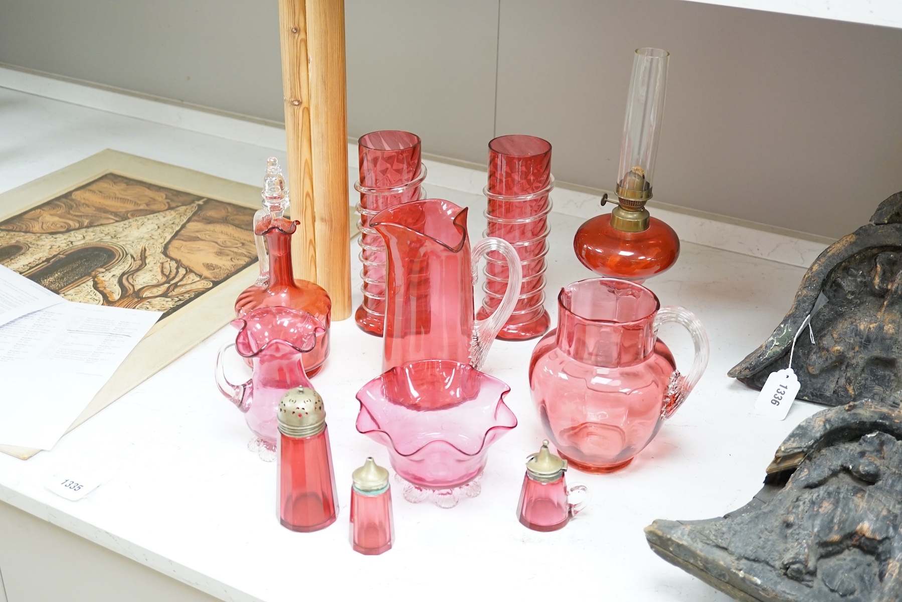 A quantity of cranberry glassware to include pair of vases with trailed decoration, jugs and an oil lamp, largest 38cm high. Condition - fair, some chipping